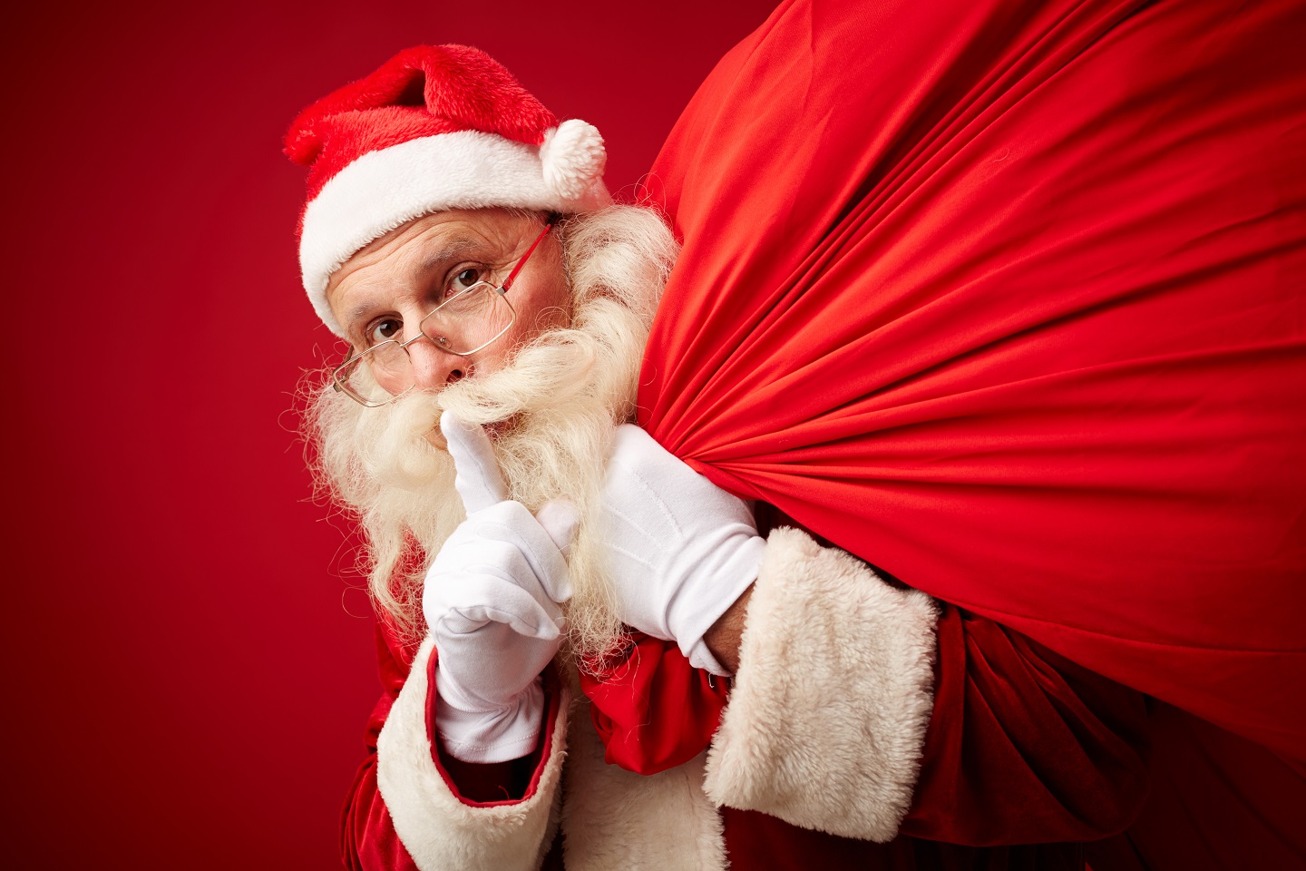 Santa with sack of xmas gifts asking for silence